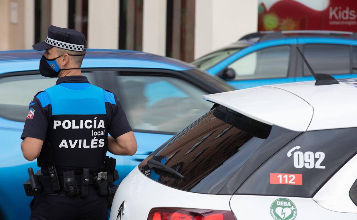 Un agente de la Policía Local junto a un coche patrulla. 