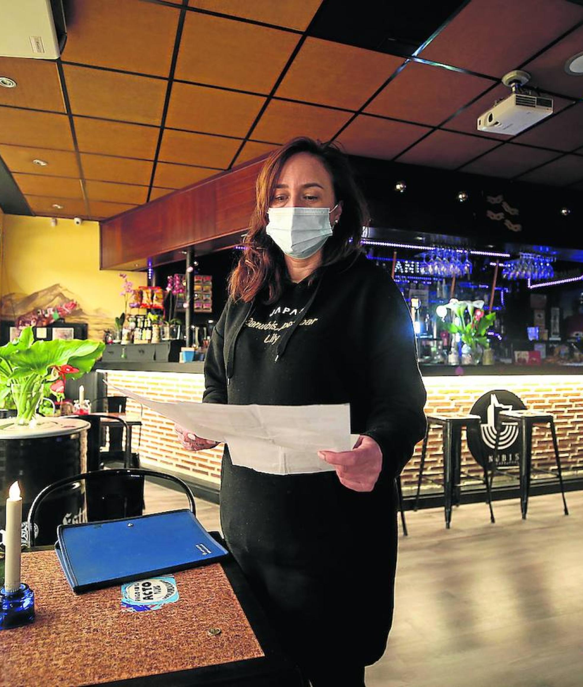 Liliana María Sánchez muestra las facturas de la luz de su establecimiento.