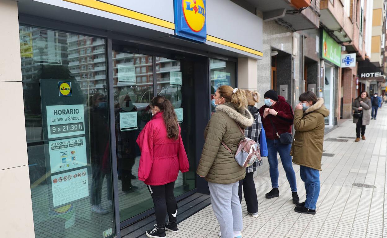 Varias personas, ante la puerta del establecimiento de Lidl de la calle Ezcurdia de Gijón, cerrado este viernes.