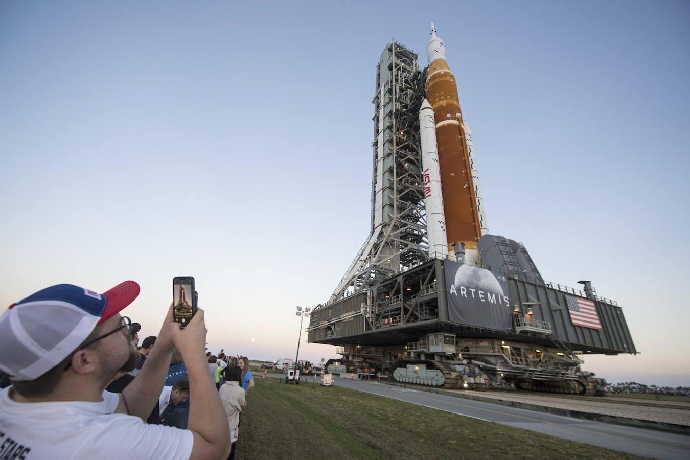 Invitados y empleados de la NASA sacan fotos del traslado del cohete hasta la plataforma de despegue. 