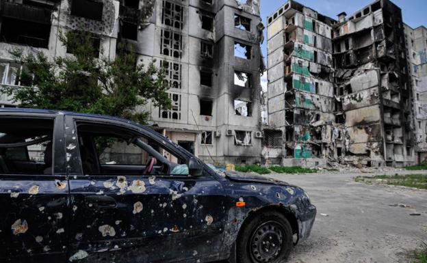 Un edificio destruido y un coche con disparos.