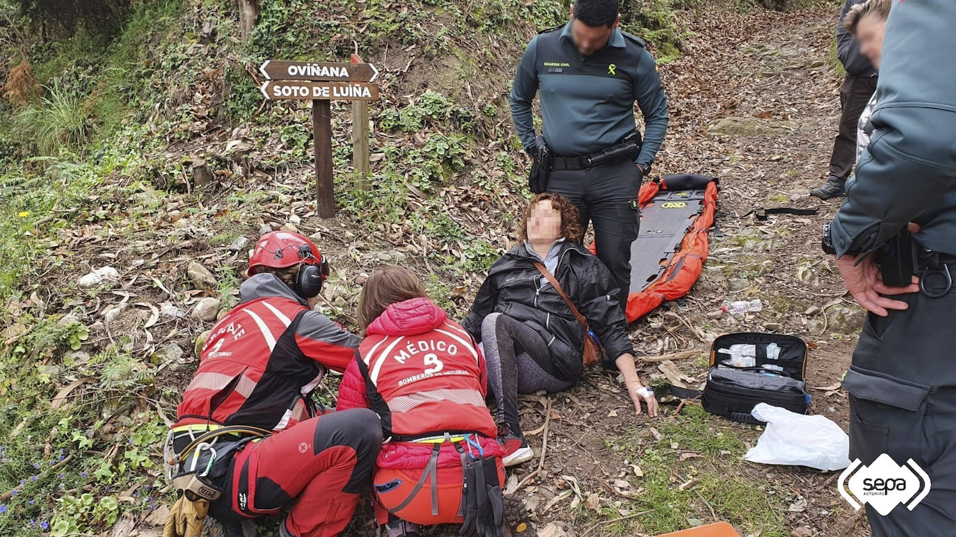 Efectivos del grupo de rescate y agentes de la Guardia Civil, junto a la senderista 
