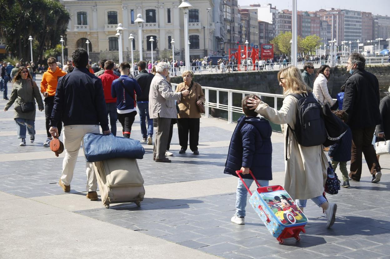 Unos turistas, con sus maletas, caminan por el paseo del Muelle. Gijón, como el resto de Asturias, rozó el lleno de ocupación esta Semana Santa. 