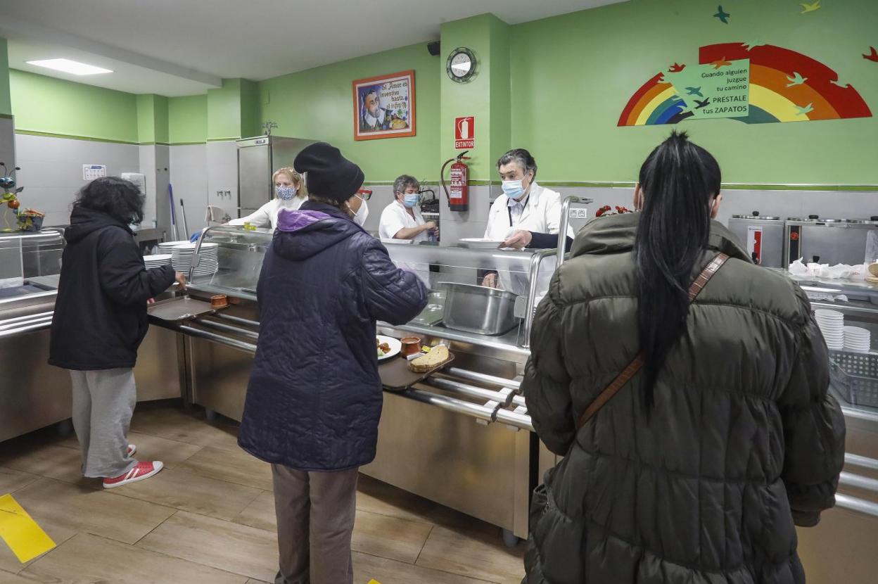 Voluntarias de la Cocina Económica, sirviendo platos a tres mujeres esta semana. 