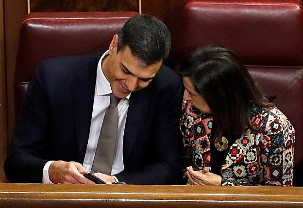 El presidente revisa su móvil junto a la ministra de Defensa en una sesión en el Congreso. 