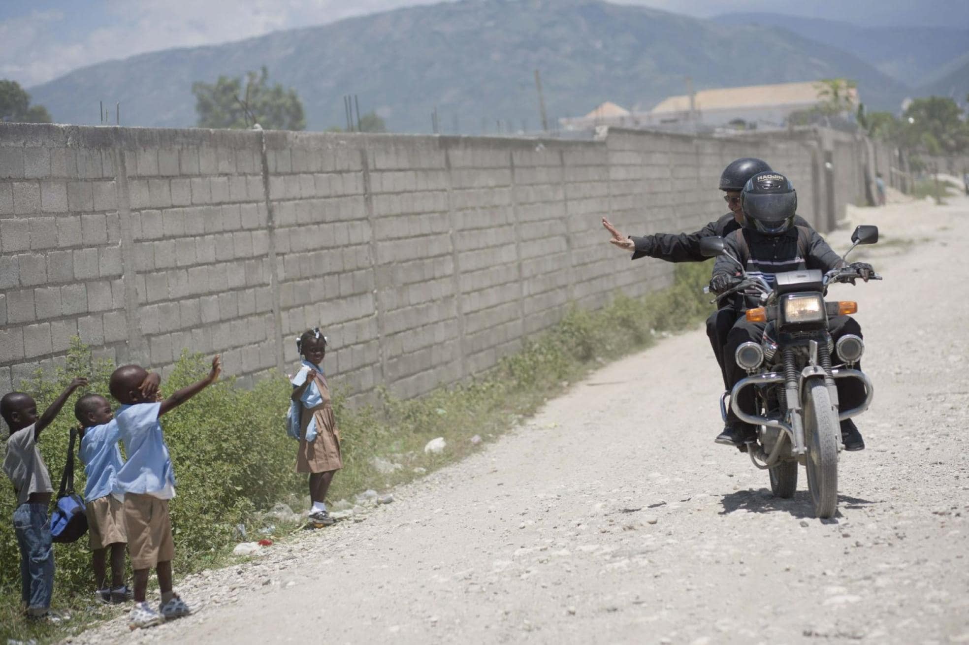 El sacerdote, en el año 2010, saluda desde una moto a un grupo de niños, en Haití.