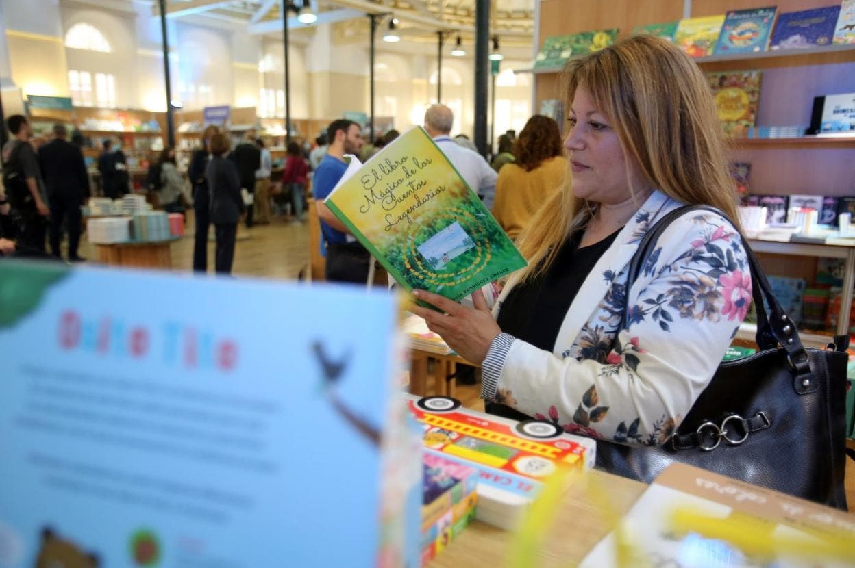 Uno de los asistentes a la inauguración de LibrOviedo en Trascorrales ojea uno de los títulos. 