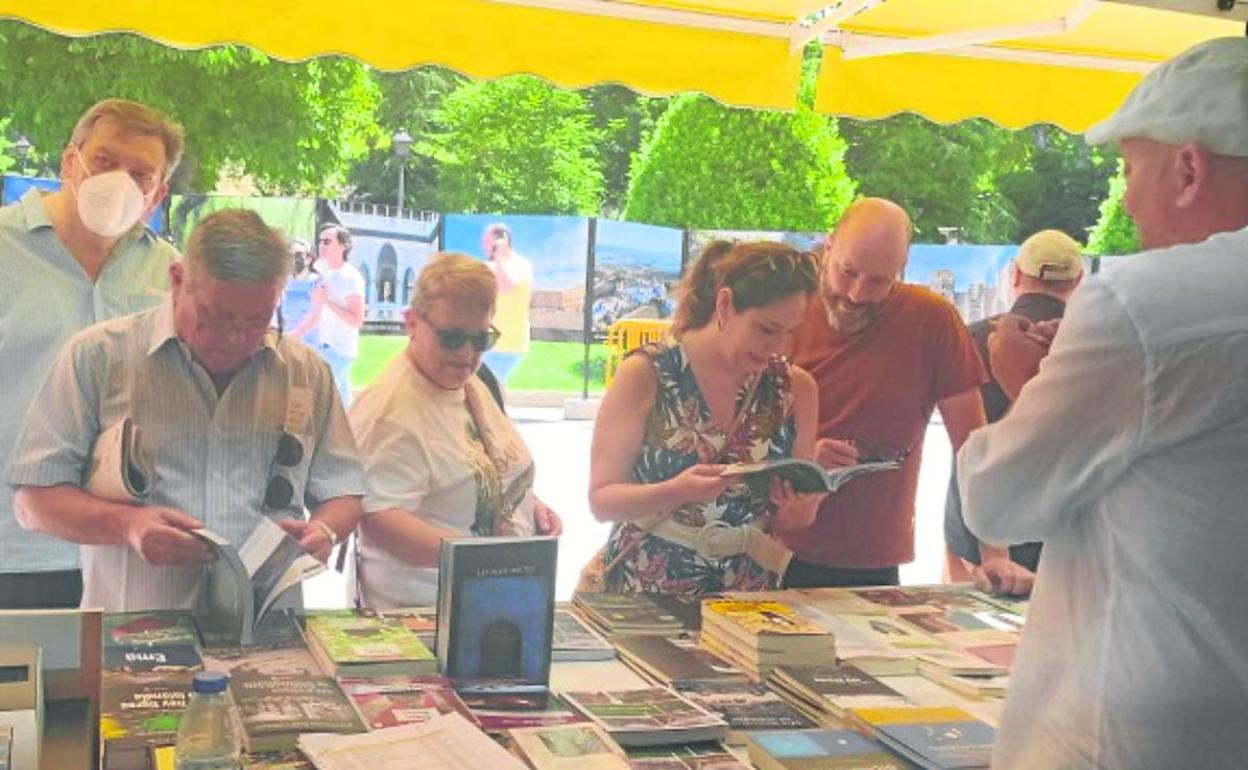 Un grupo de clientes mira los libros que ofrecen las editoriales asturianas en la Feria del Libro. 