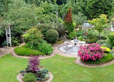 Imagen secundaria 1 - Vista general del jardín con el cenador en medio y los parterres cerrados con rocalla en torno al mismo; y ceanothus en plena floración con la casita de juegos infantiles detrás.