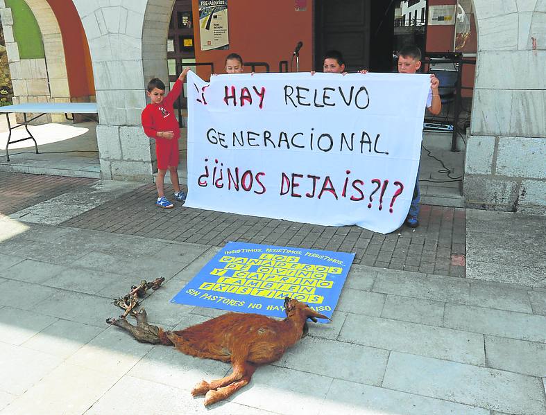 Hijos de ganaderos, con una pancarta tras una cabra muerta. pardo