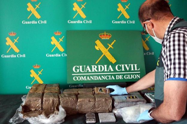 Un agente de la Guardia Civil con el alijo de droga incautado en la vivienda del barrio de Montevil. 