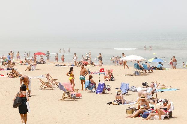 Gijón. Los bañistas en la playa de San Lorenzo entre niebla. 