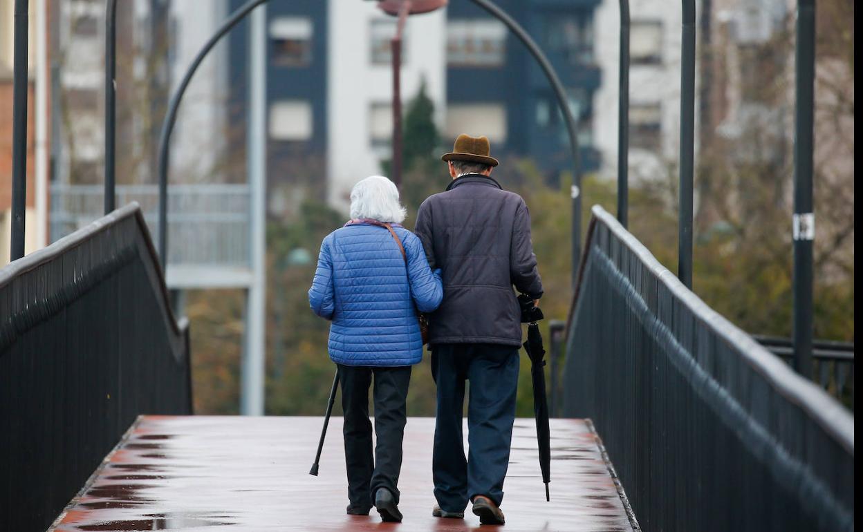 Una pareja de personas mayores camina por Gijón 