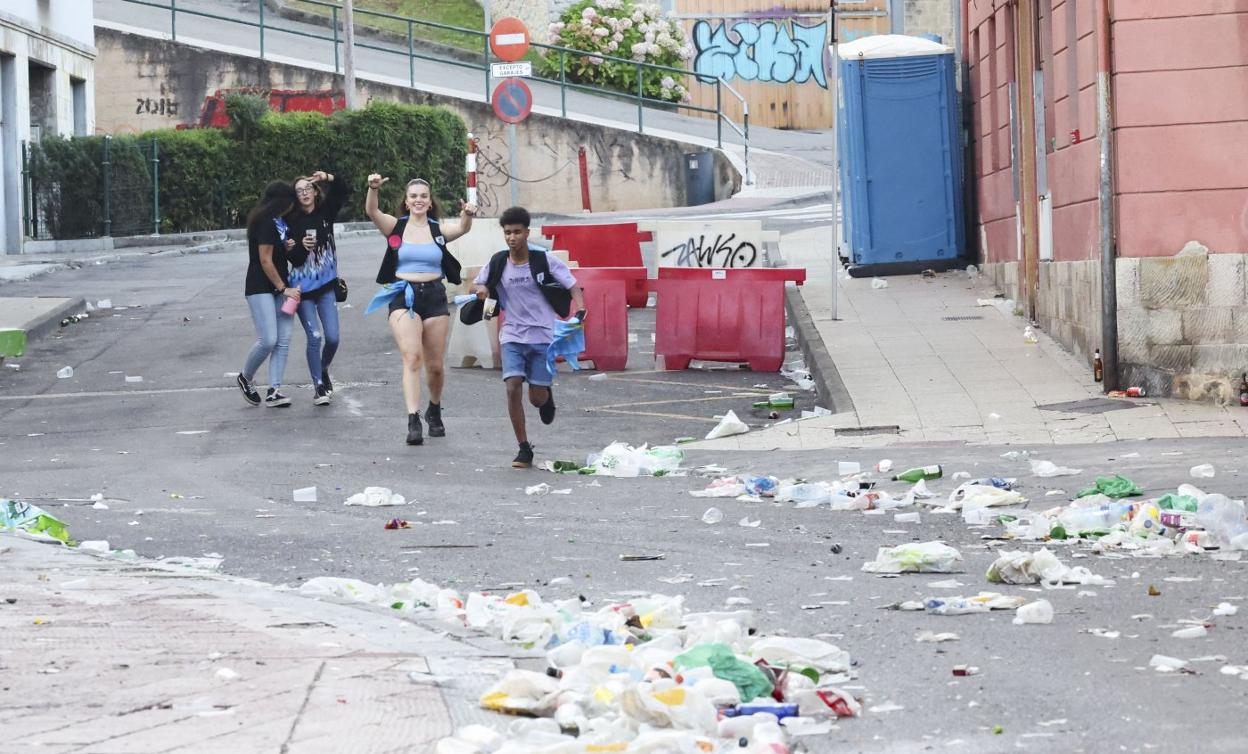 Cuatro jóvenes, en una calle de Ribadesella, repleta aún de los restos de la fiesta. 