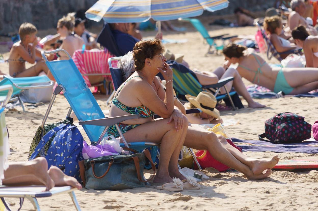 Una mujer en la playa de San Lorenzo fumando un cigarro. 