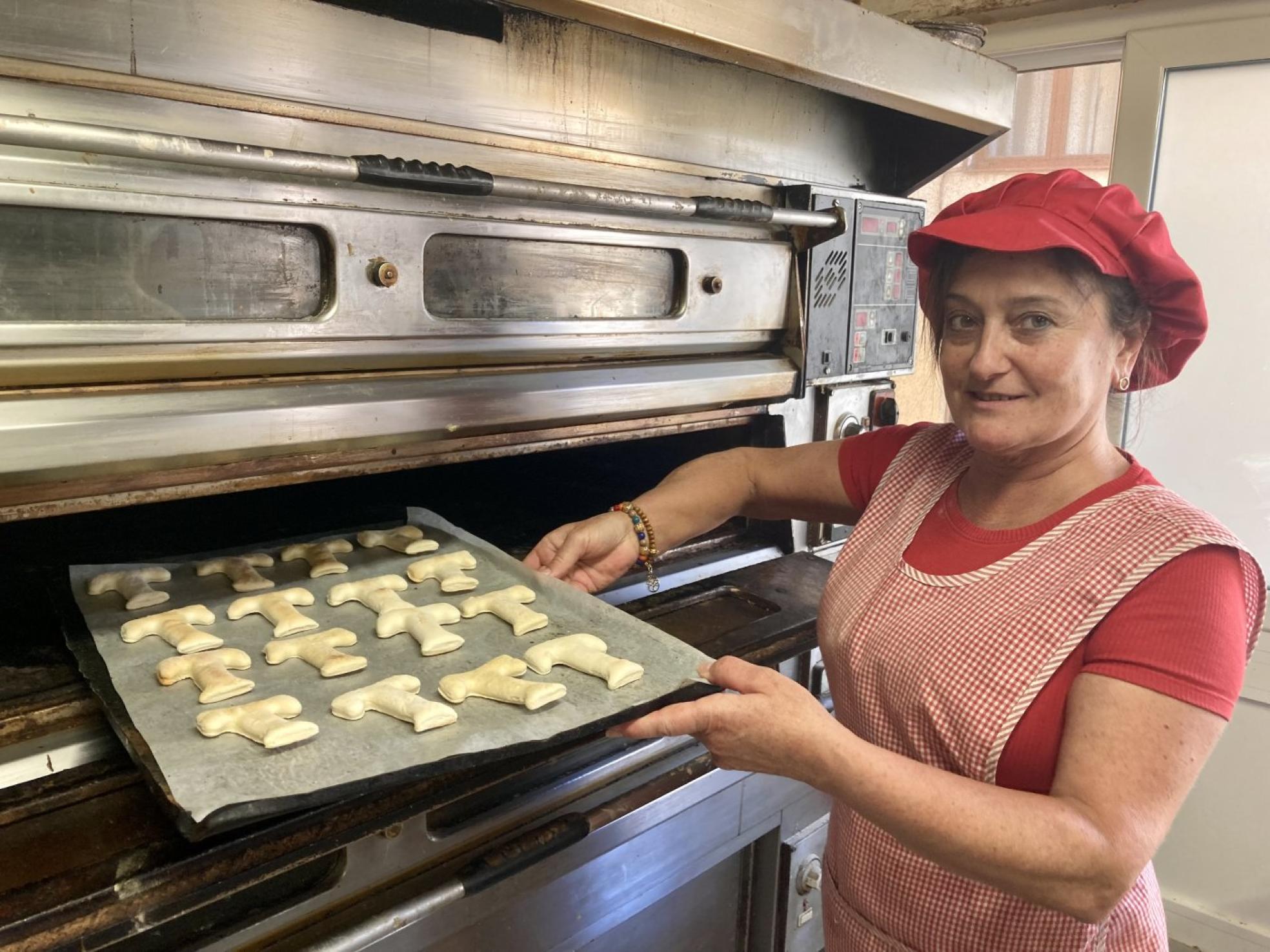 Una de las trabajadoras de la Panadería Aldín saca las tradicionales T's del horno, que vende a favor de la asociación contra el cáncer. 