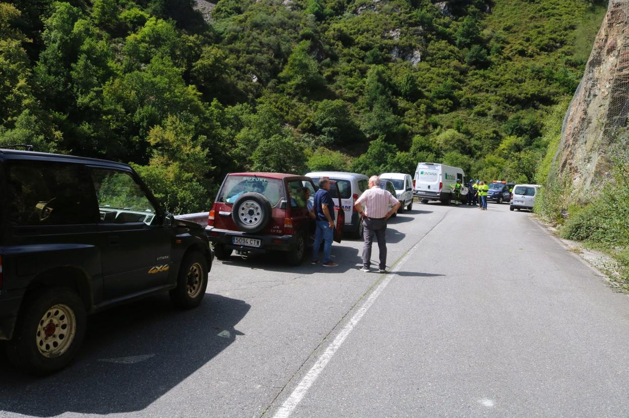 La grúa termina, sobre estas líneas, el saneamiento de la zona. A la derecha, arriba, el punto más elevado del talud. Abajo, conductores a la espera de cruzar a pie tras dejar su vehículo en un lateral de la carretera. 