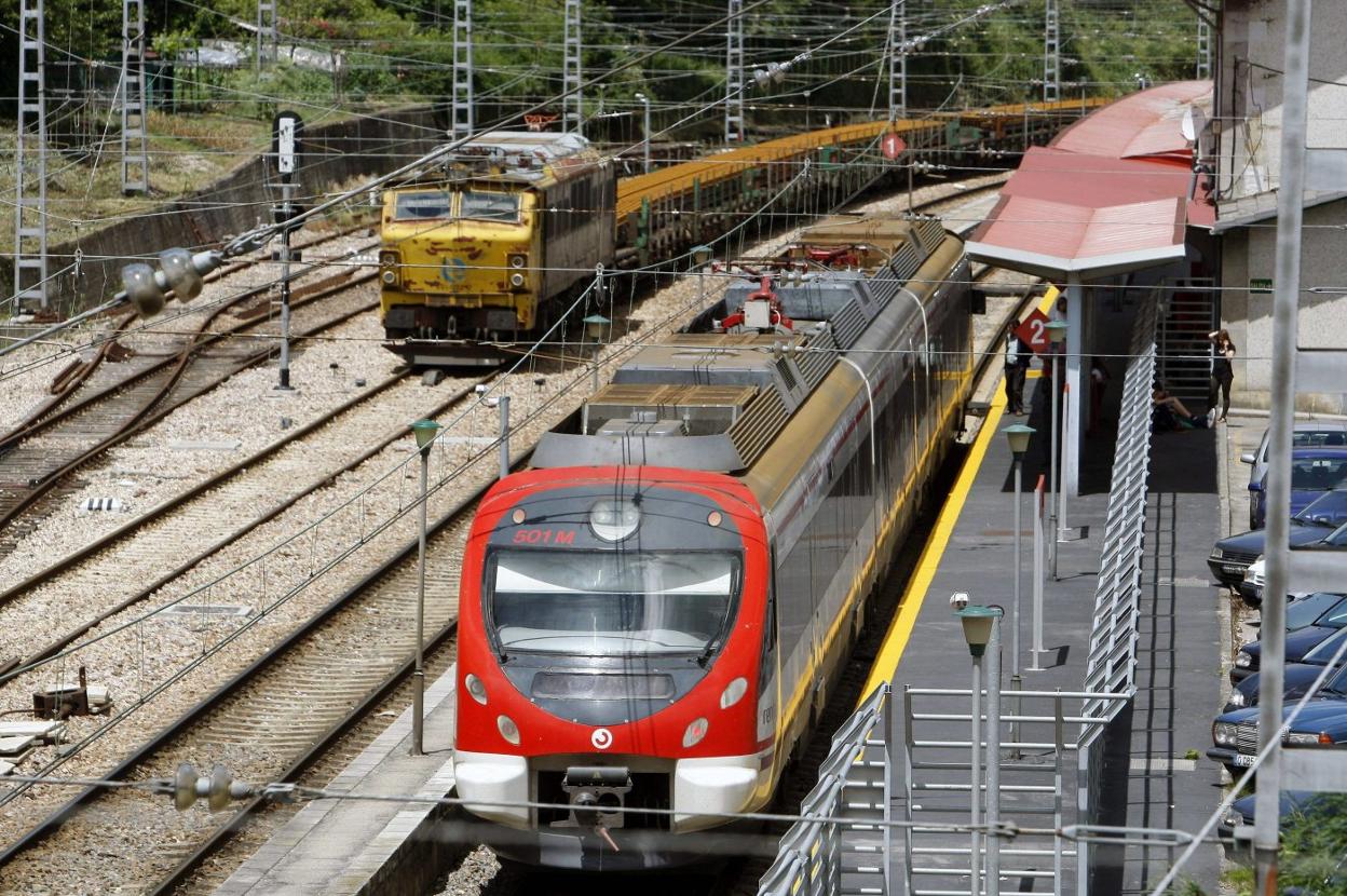 Un tren de mercancías entra en la estación de Pola de Lena, donde otro de pasajeros está parado. 