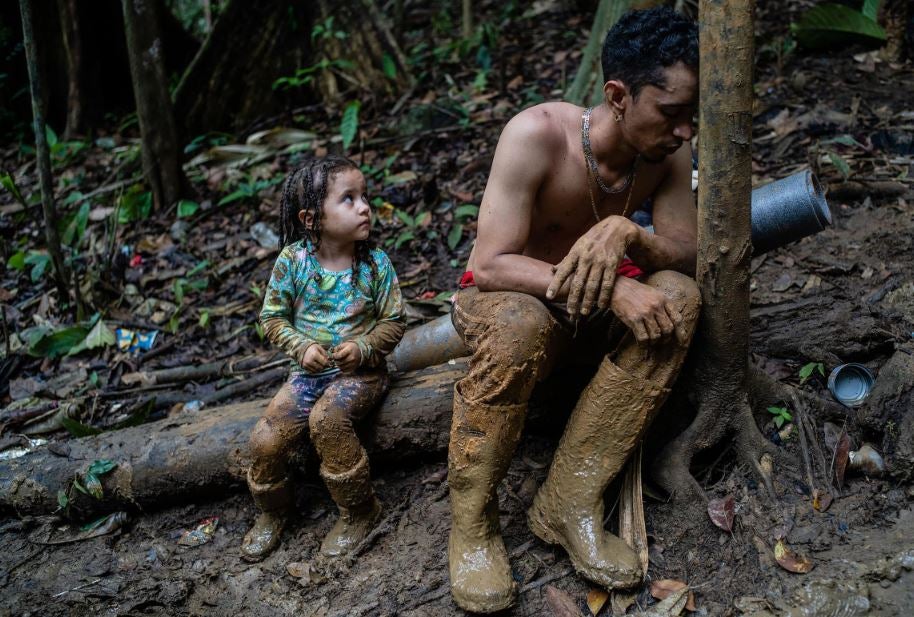 Un hombre y un niño, exhaustos, descansan en el Tapón de Darién. Les queda una semana de caminata aún por delante a través del tramo de terreno selvático de 66 millas entre Colombia y Panamá, el 23 de septiembre.