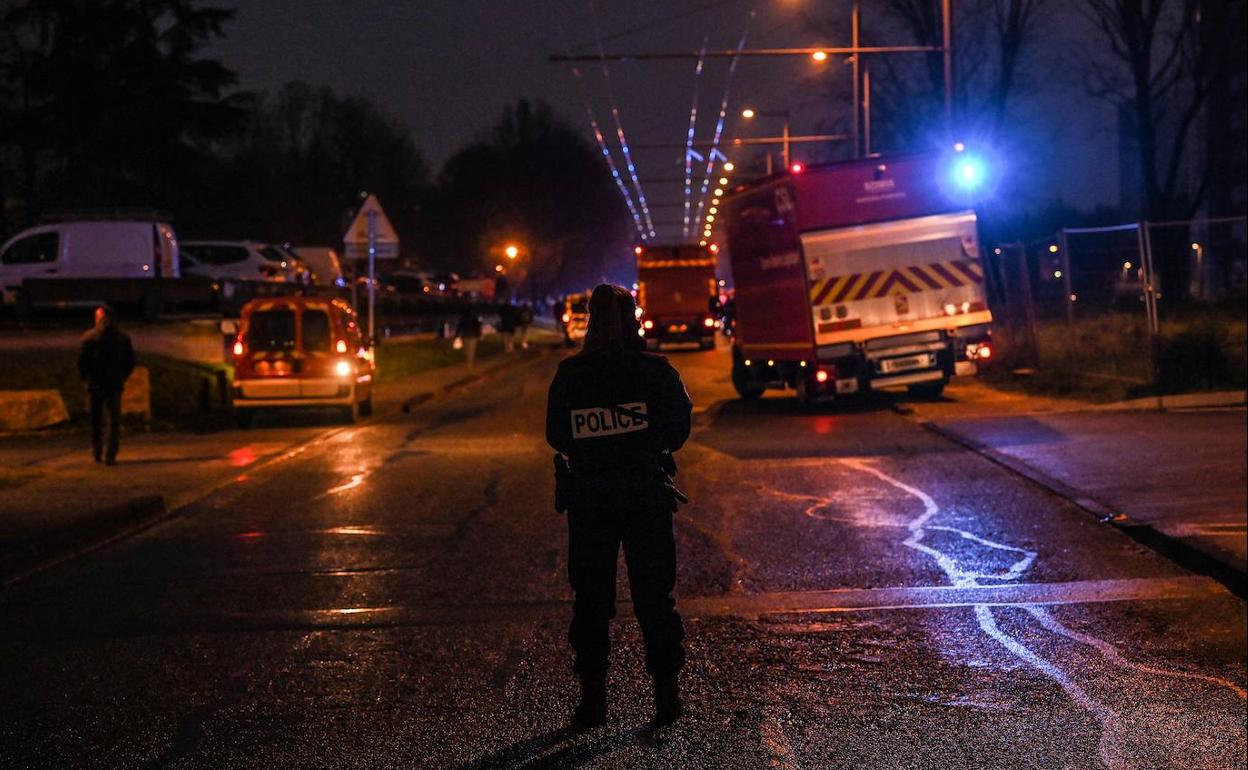 Los policías vigilan un perímetro de seguridad mientras los bomberos trabajan en el edificio afectado por el fuego. 