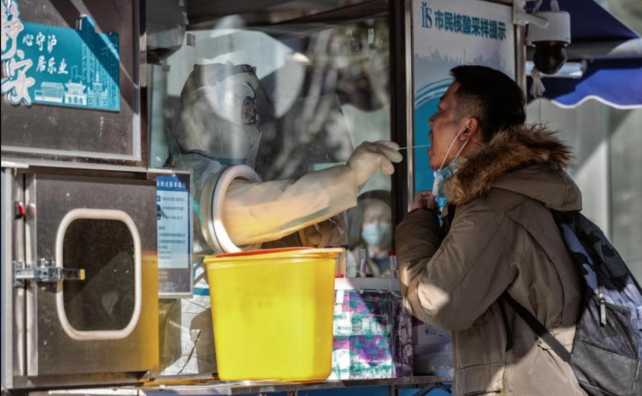 Un sanitario realiza a través de una pantalla protectora una prueba PCR a un ciudadano en Shanghái. 