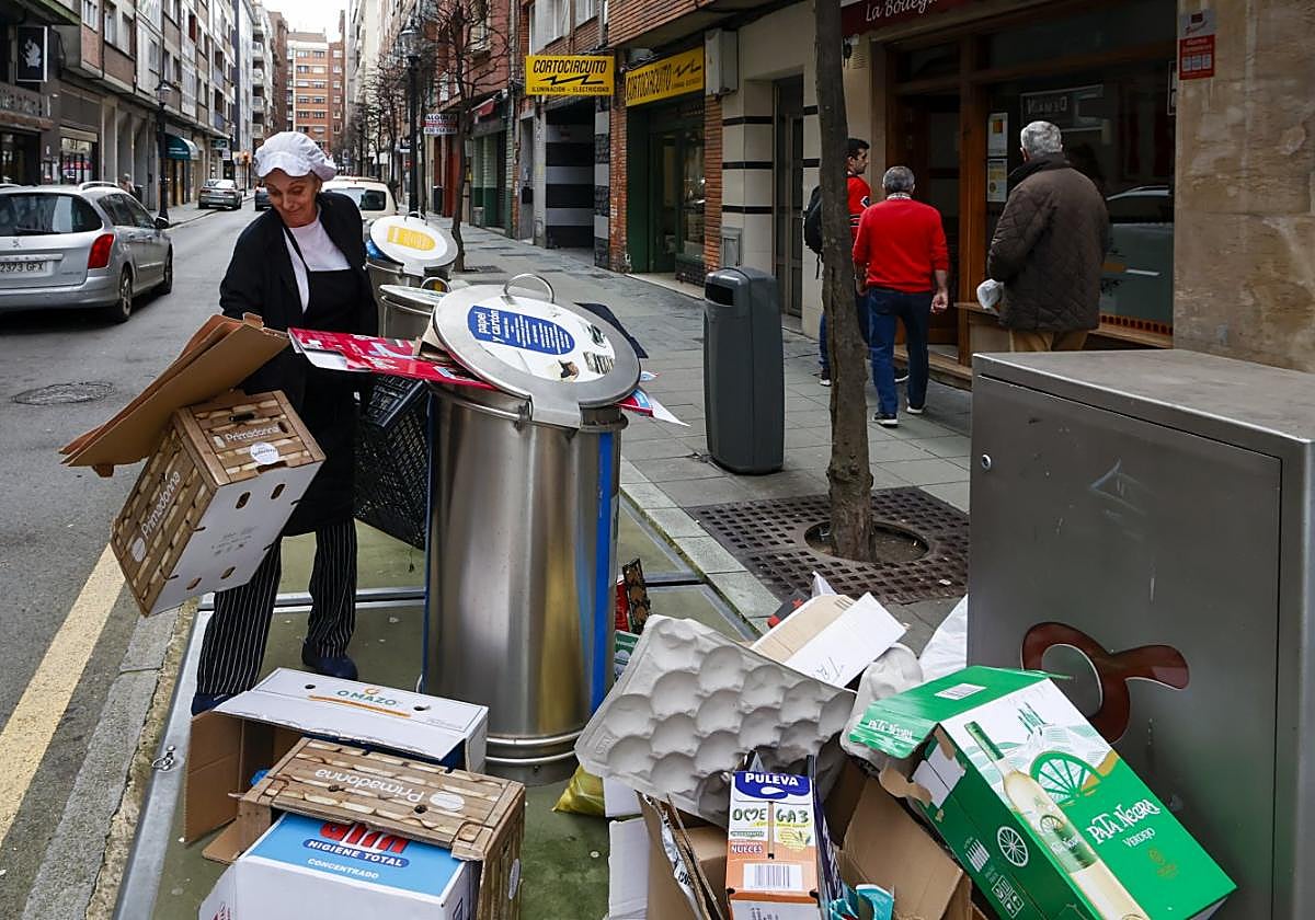 La cocinera de un restaurante pulpería de la calle Aquilino Hurlé de Gijón deposita cartón junto al contenedor.
