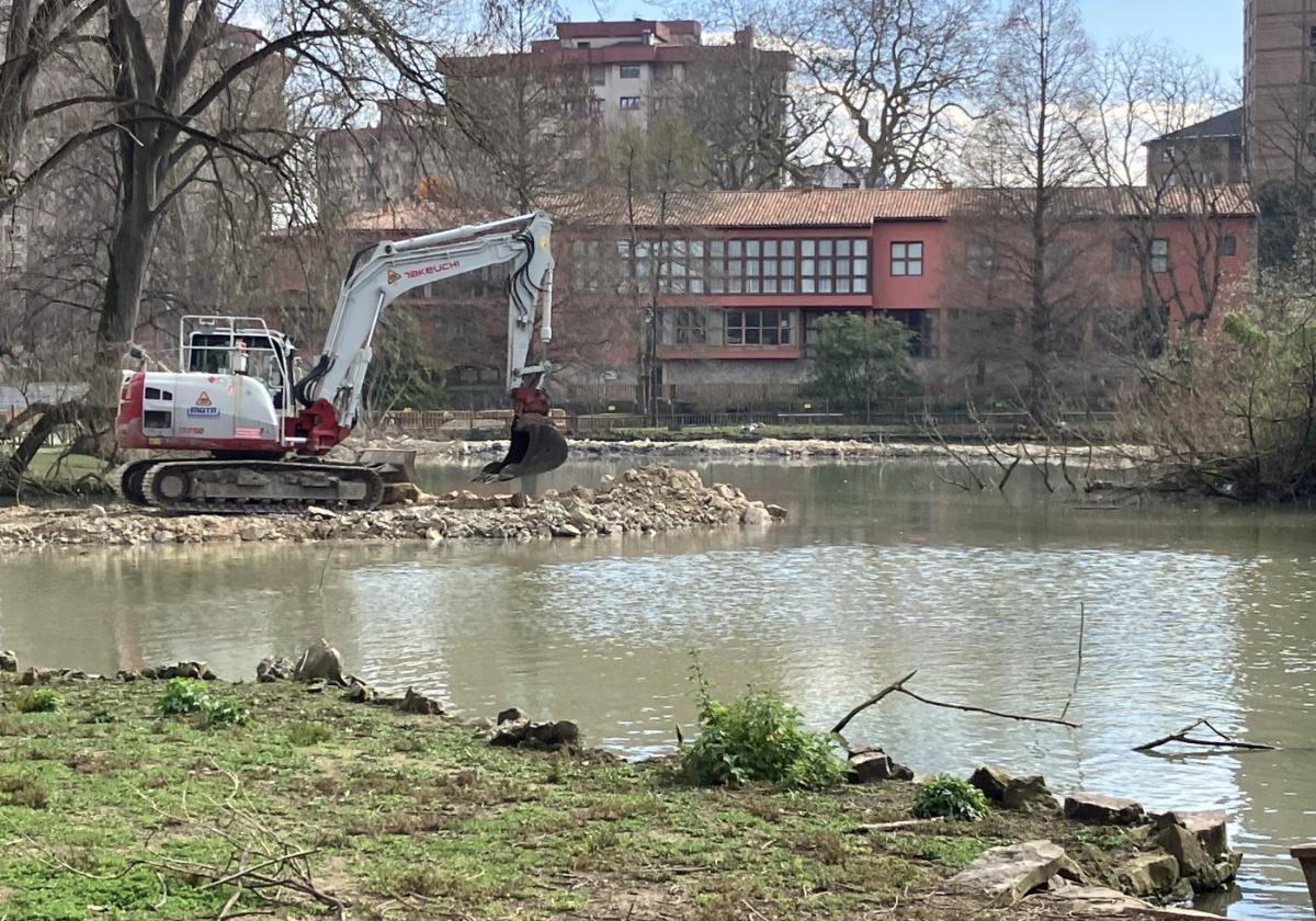 Una excavadora ayer haciendo diques en el estanque grande del parque para poder acumular allí lodos.