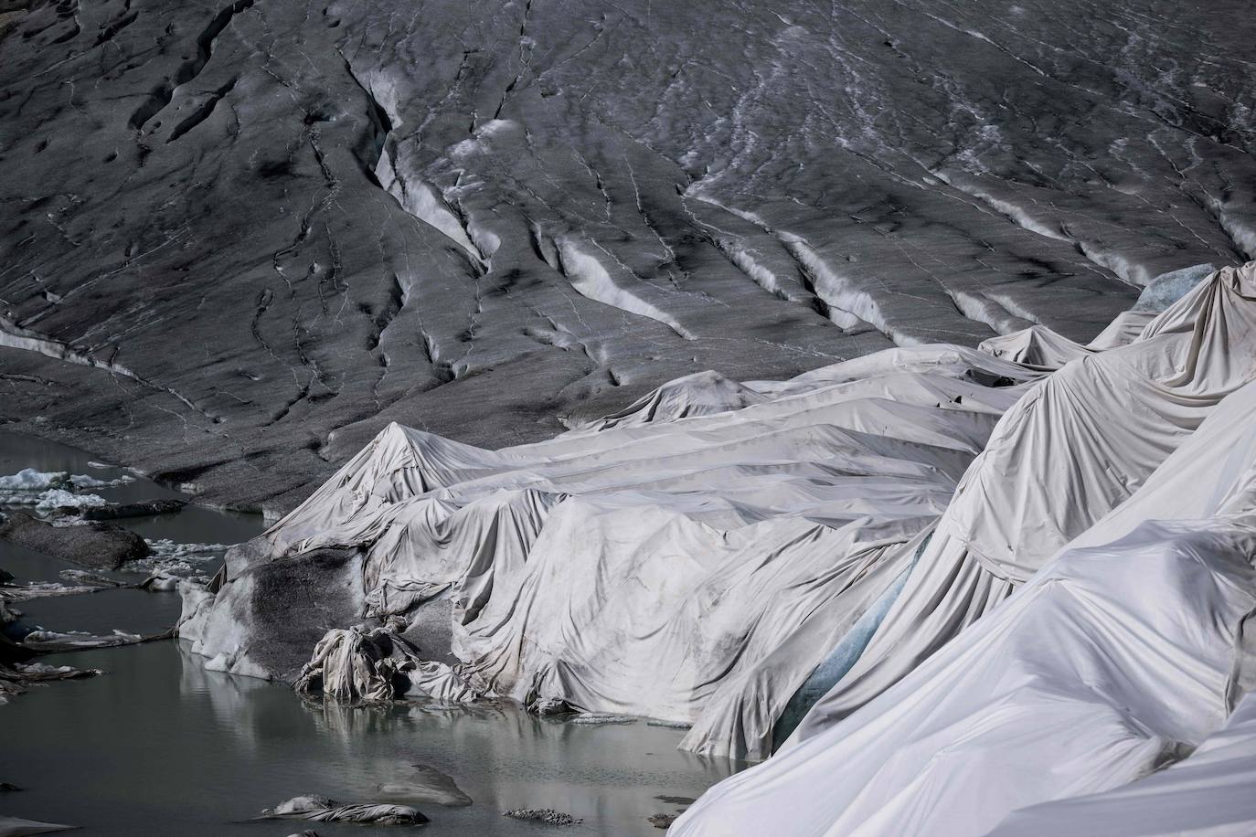 Esta fotografía tomada cerca de Gletsch, en los Alpes suizos, el 8 de julio de 2022 muestra la tela aislante que cubre una parte del glaciar del Ródano para evitar que se derrita junto a su lago glaciar, formado por el derretimiento del glaciar debido al calentamiento global.