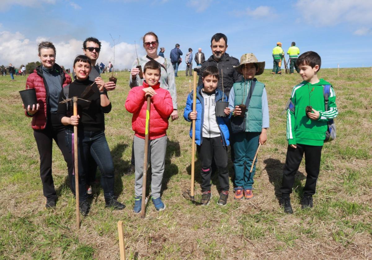 Varios niños y sus padres posan con las macetas y los útiles para plantar sus primeros árboles.