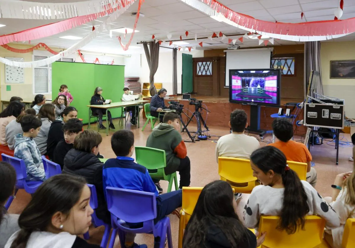 Los alumnos presencian la grabación del informativo de televisión en el salón de actos del colegio, convertido en un plató por una mañana.