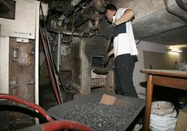 Un hombre alimenta una de las calderas de carbón de un edificio de Gijón.