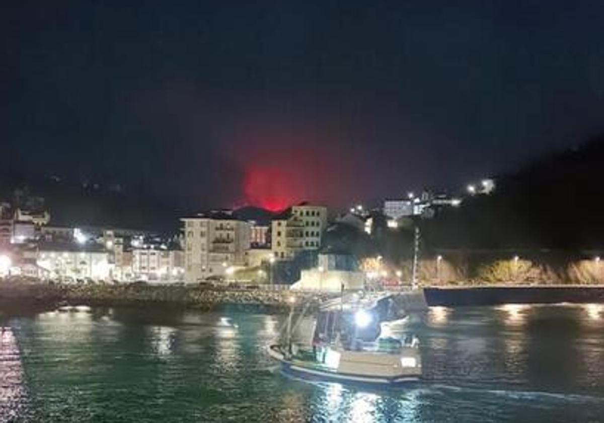 Desde el muelle de Luarca, el fuego se asoma en Aristébano.