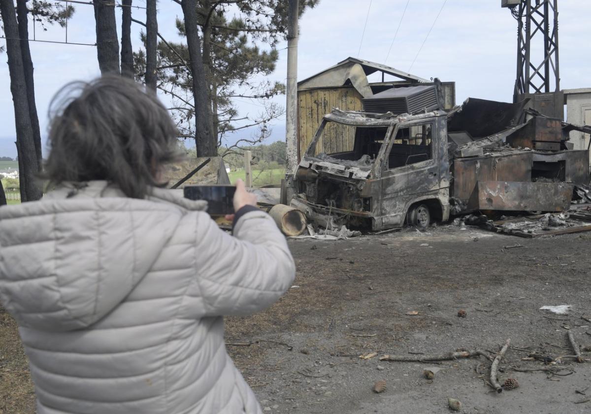 Una mujer fotografía una camioneta calcinada en Valdés.