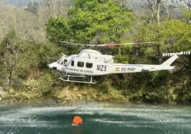 Un helicóptero recoge agua en el río Sella.