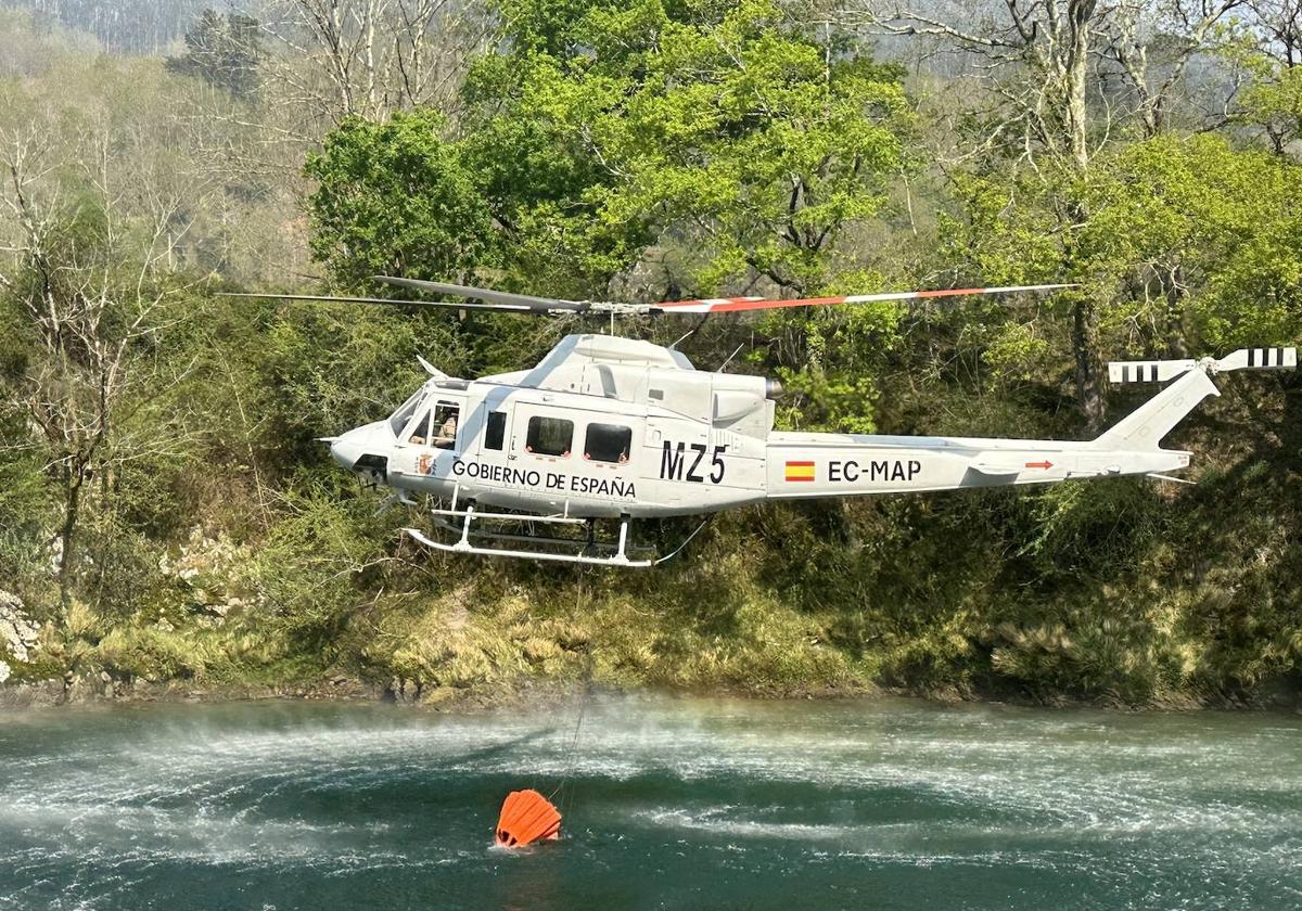 Un helicóptero recoge agua en el río Sella.