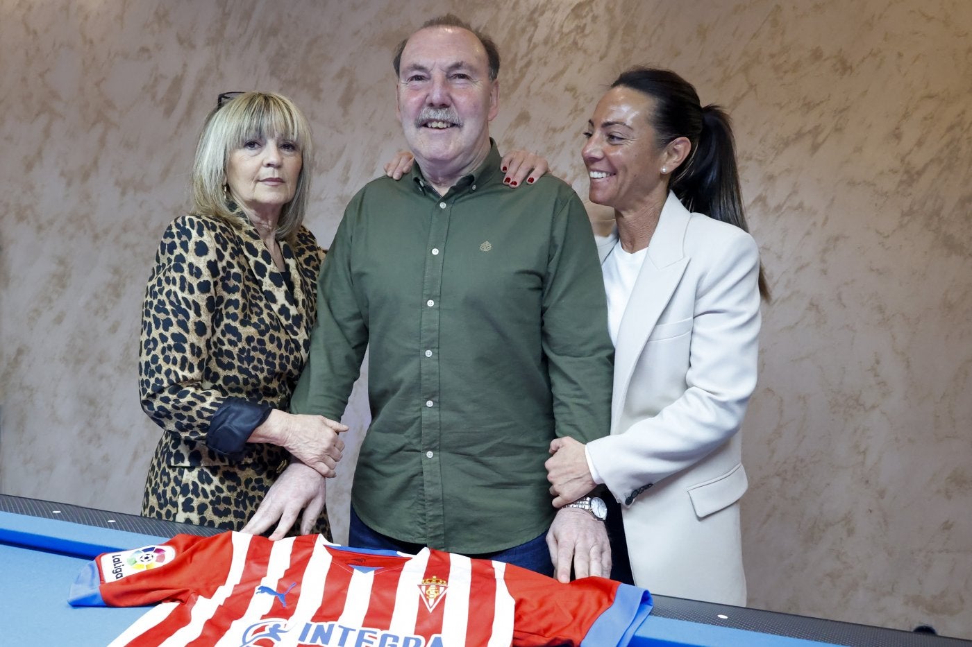 Cundi, ayer, en el café 'El Quince', en Nuevo Roces, entre Marga, su mujer, y su hija Mayra, sujetando la camiseta del Sporting.