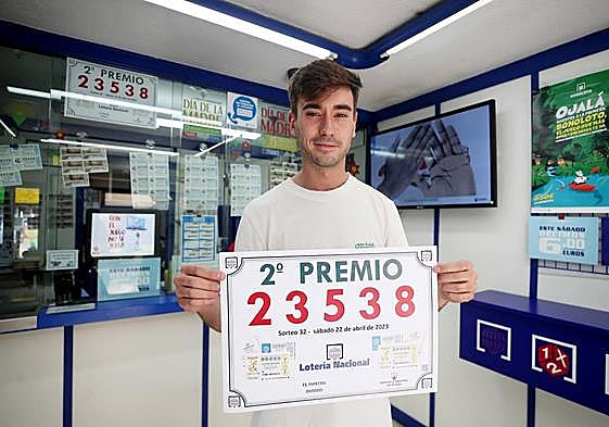 El lotero de la administración ovetense número 21 de la calle Fierro posa con el cartel del número dotado con el segundo premio de la Lotería Nacional.