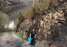 Xuan González, de once años y con la regadera con la que ayudó a luchar contra el fuego, y su perra 'Gala', junto al monte quemado.