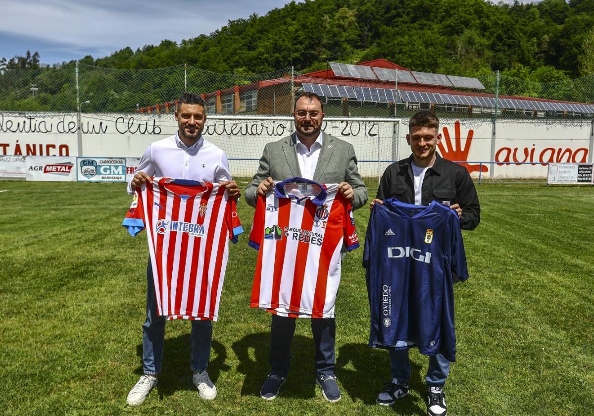 Adrián Barbón, con la camiseta conmemorativa con la que le obsequió el Titánico en Las Tolvas, con Canella y Viti, sujetando las del Sporting y del Oviedo.