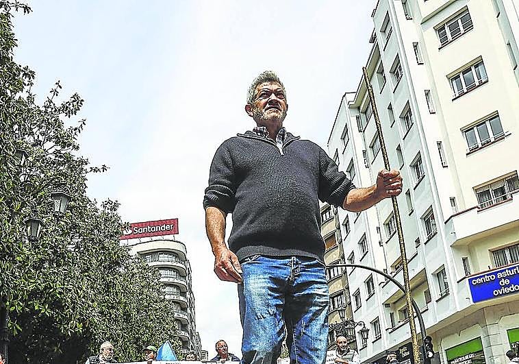 Un ganadero marcha por la calle Uría ante una pancarta de protesta.