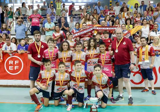 Los jugadores del Gijón Industrial con los técnicos Óscar Rancaño y Javier Carriles posan con las medallas y su trofeo delante de su afición, este mediodía, en La Arena