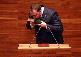 Adrián Barbón besa la Biblia antes de guardarla en un cajón bajo el atril donde prometió el cargo de diputado sobre la Constitución y el Estatuto de Autonomía.