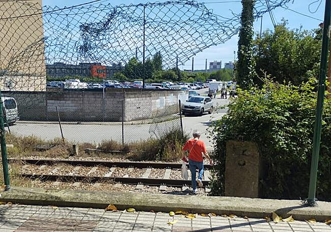 Una persona cruza la vía del tren por un hueco abierto en las vallas de seguridad instantes después de lo ocurrido, cuando el tráfico ferroviario se encontraba detenido.