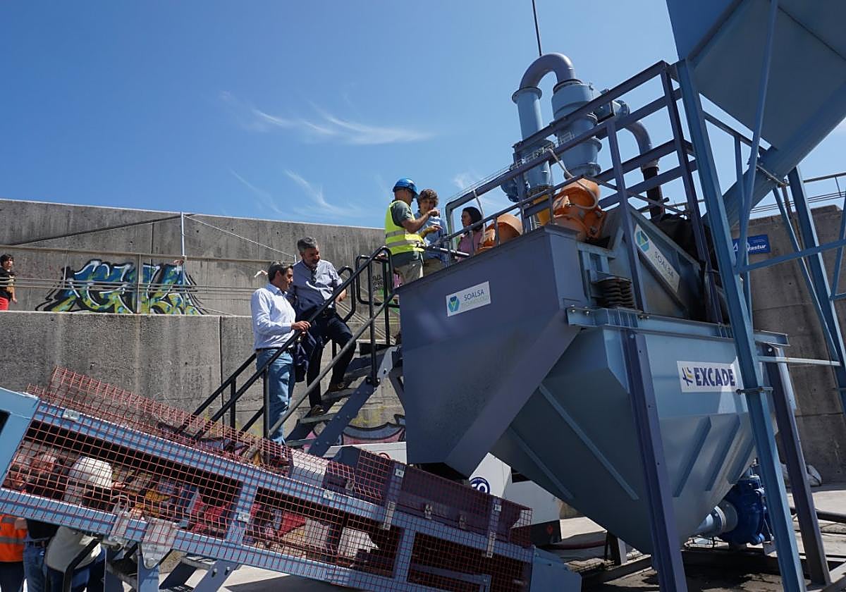 Francisco González y Alejandro Calvo contemplan la máquina 'Ciclón' en el puerto de Llanes.