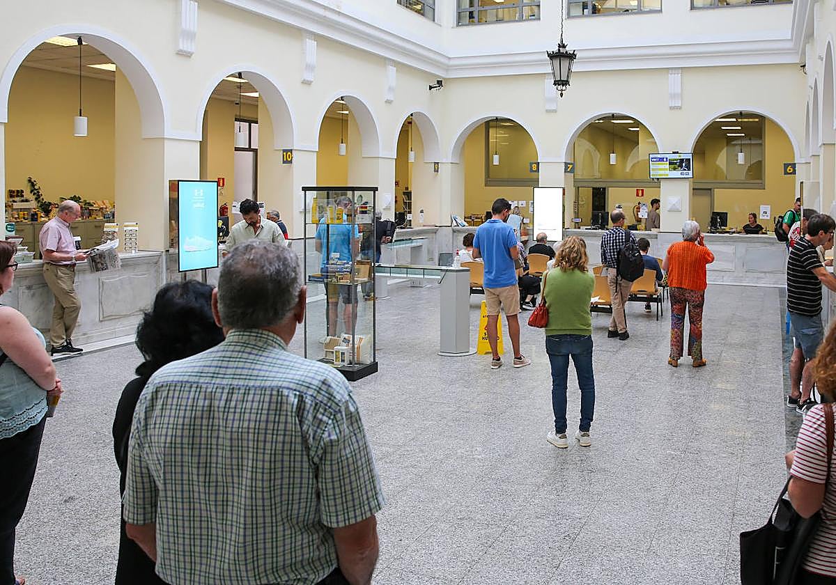 Ciudadanos esperan a ser atendidos en la oficina central de Correos de Gijón.