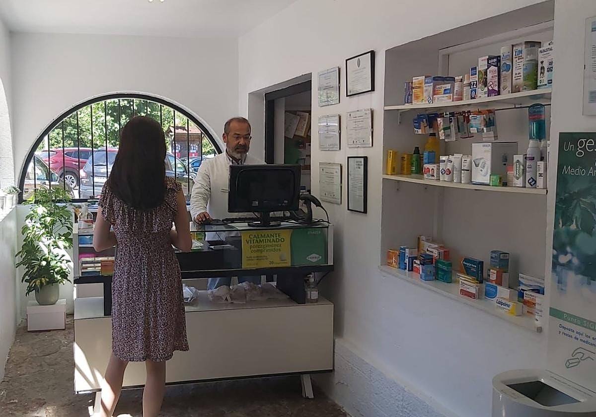 Jaime Espolita atiende a una clienta en su farmacia de Santillán.
