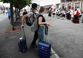 Dos turistas observan un espectáculo folclórico en Gijón el pasado domingo.