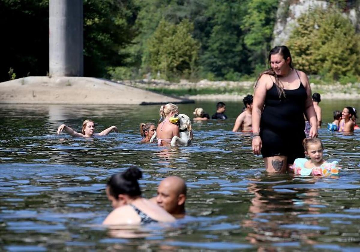 Varias personas se refrescan en el Nalón, a la altura de las Caldas.