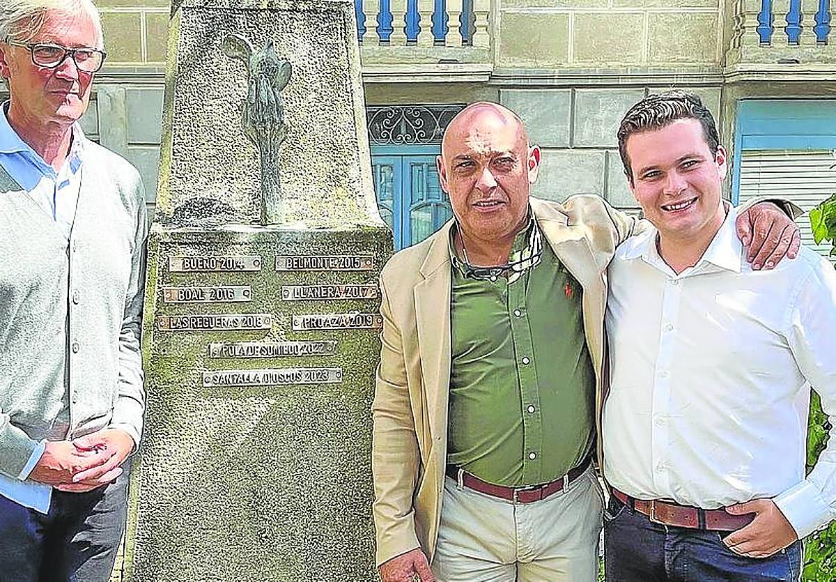 Marcos Niño, Luis López y Sergio Martínez, con el monolito del los Pueblos de Asturias de Navelgas en el que desde ayer figura también Santa Eulalia de Oscos.