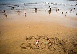 Dos niños, tumbados en la playa de San Lorenzo en plena ola de calor.